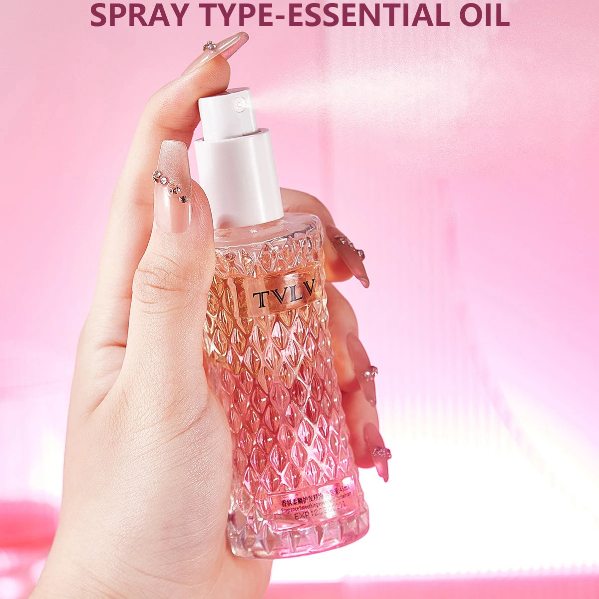 Hand holding a TVLV essential oil spray bottle against a pink background